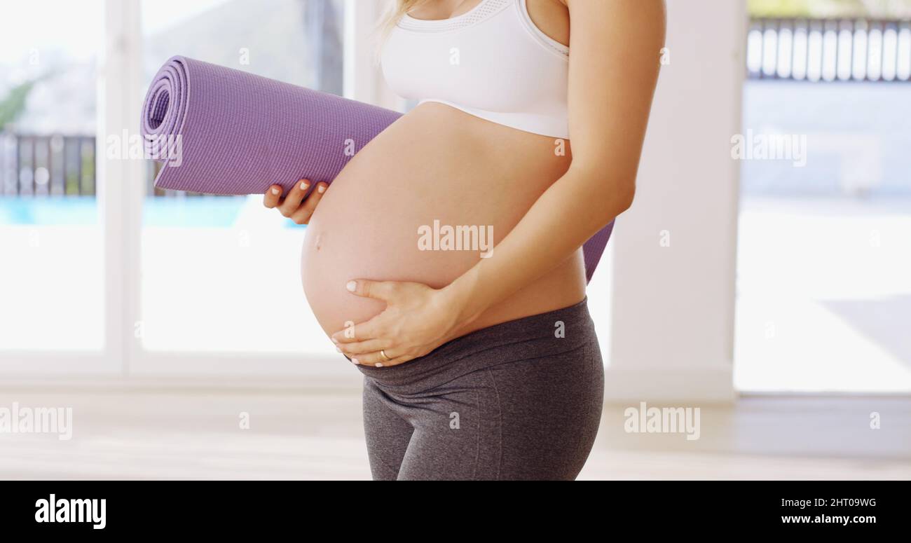 Mi hanno detto che lo yoga era buono per il bambino. Scatto corto di una giovane donna incinta irriconoscibile che porta un tappeto yoga. Foto Stock