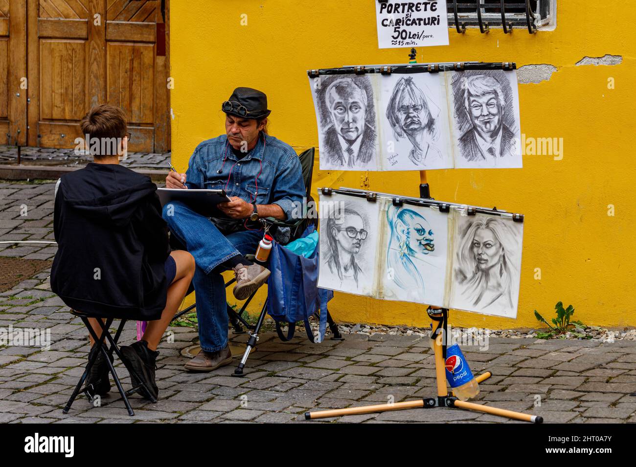 Un artista di pittura sta disegnando ritratti nelle strade di Sighisoara in Romania Foto Stock
