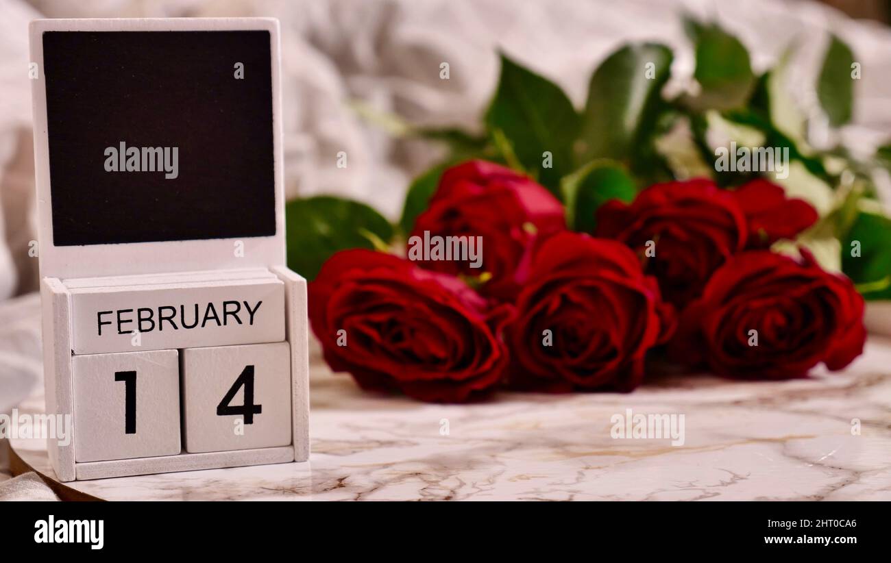 Festa Flatlay, composizione per San Valentino il 14 febbraio. Caffè in una tazza rossa e fiori rossi di rosa a casa a letto Foto Stock