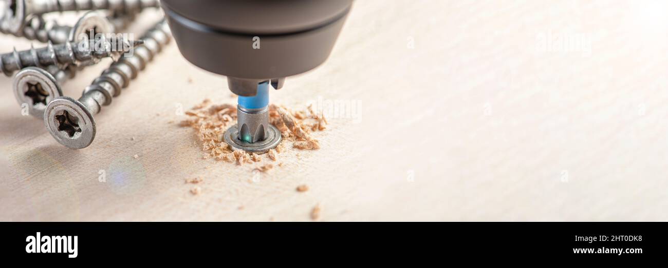 Produzione di mobili in legno. Avvitando una vite in un mobile. Assemblaggio di mobili in legno in primo piano Foto Stock