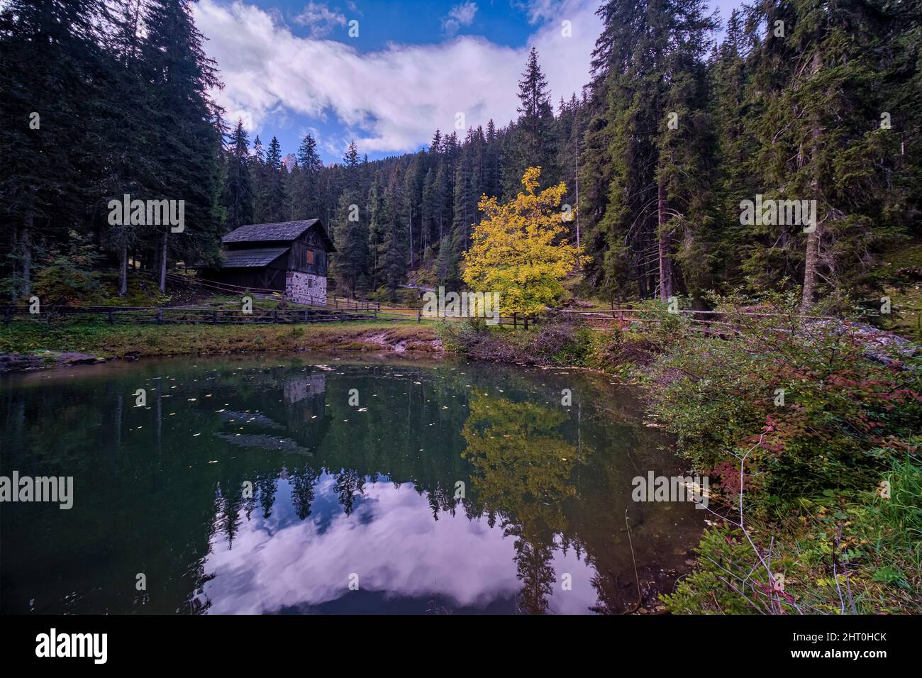 Una casa su un lago nel mezzo di una foresta sulla strada per Malga Geisler in autunno. Foto Stock