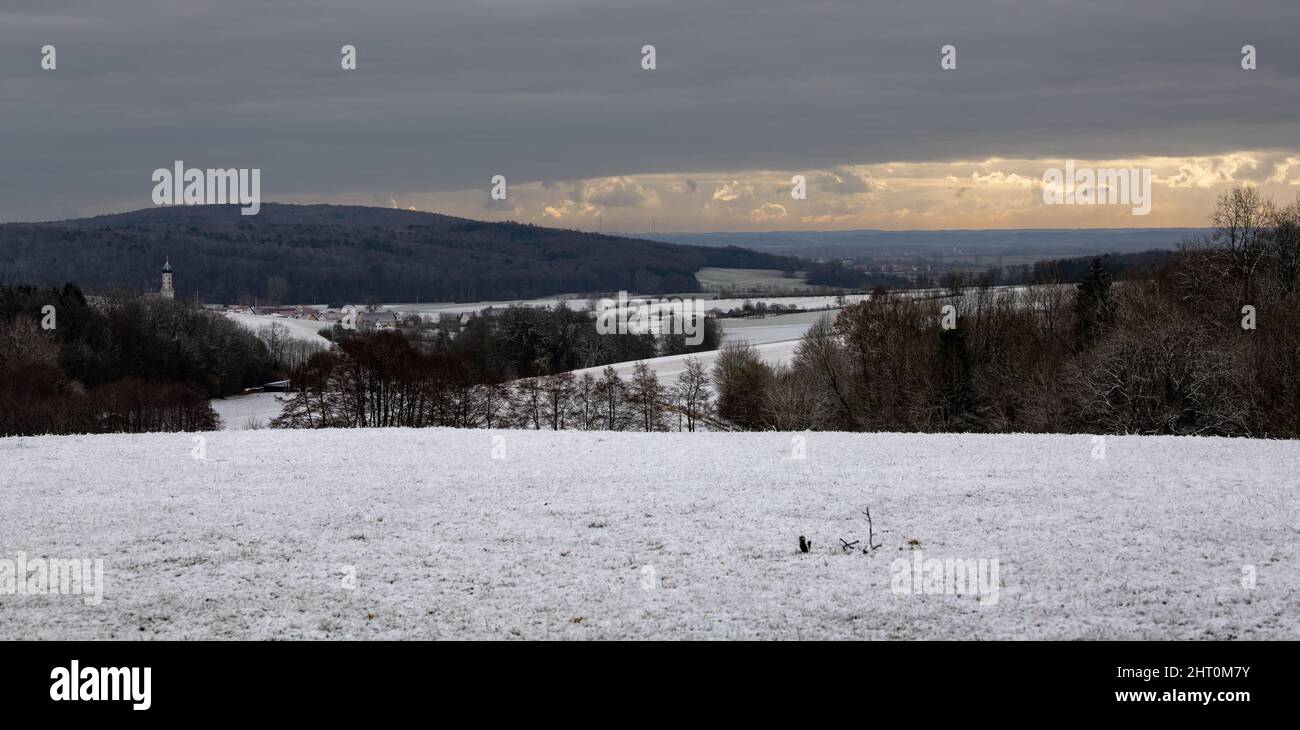 26 febbraio 2022, Baviera, Mödingen: Il cielo coperto si rompe dietro prati nevosi. Il tempo è instabile, ma dovrebbe diventare più solario nei prossimi giorni. Foto: Stefan Puchner/dpa Foto Stock