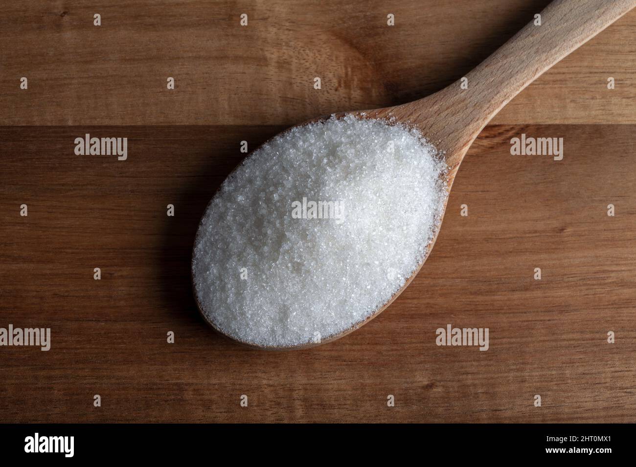 Cucchiaio pieno di zucchero su sfondo di legno Foto Stock
