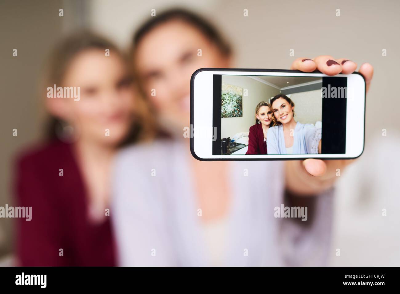 Matrimonio mattina vibes. Scatto corto di una bella sposa giovane e la sua migliore amica prendendo un selfie insieme nel loro spogliatoio prima del matrimonio. Foto Stock