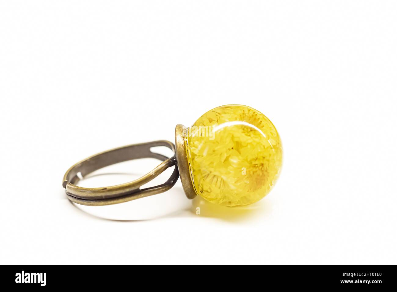 Un anello in ottone fatto a mano con fiori secchi gialli isolati su sfondo bianco Foto Stock