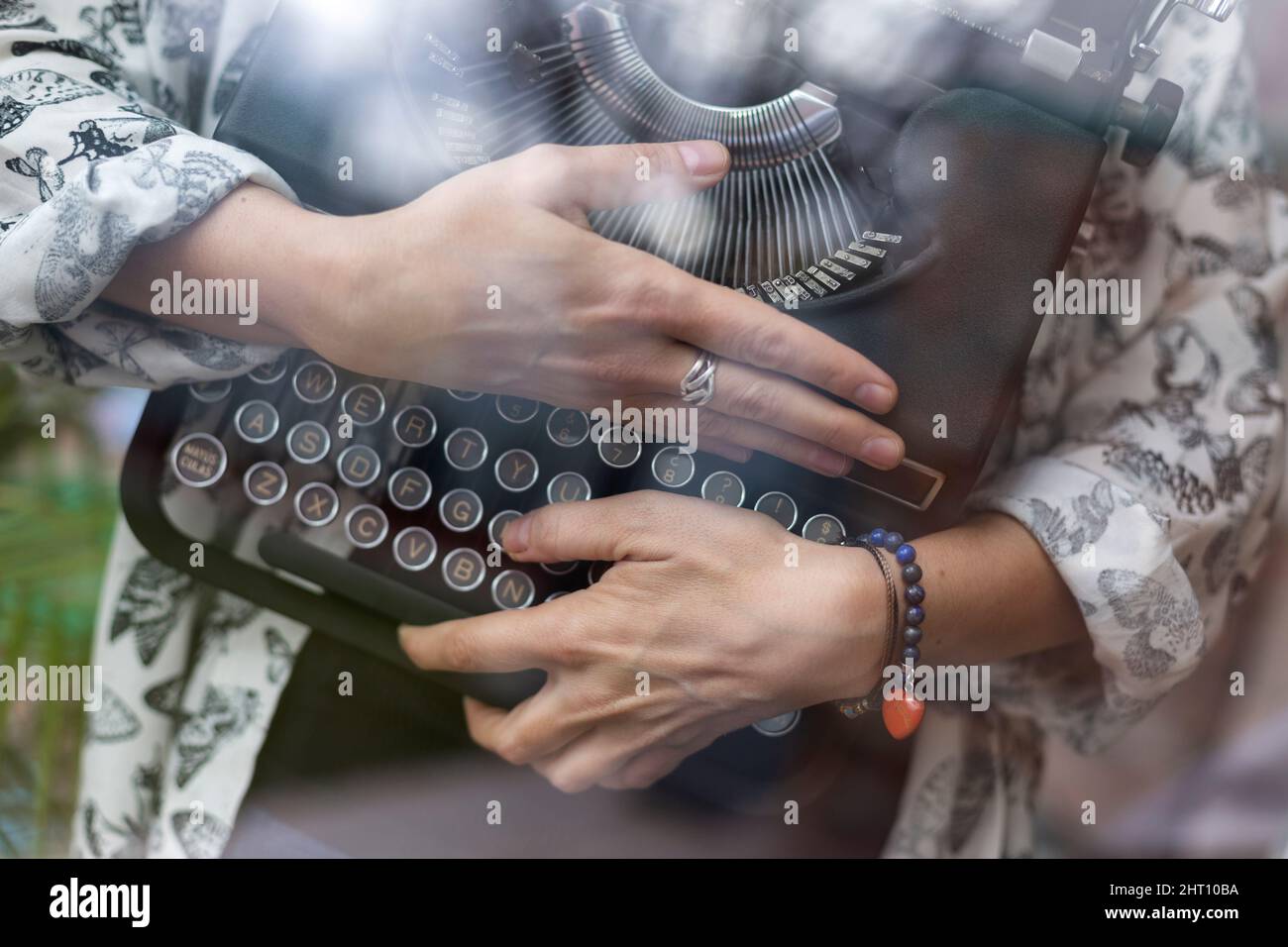 Primo piano di una persona irriconoscibile che abbraccia una macchina da scrivere classica. Concetto di passione e amore per la scrittura. Foto Stock