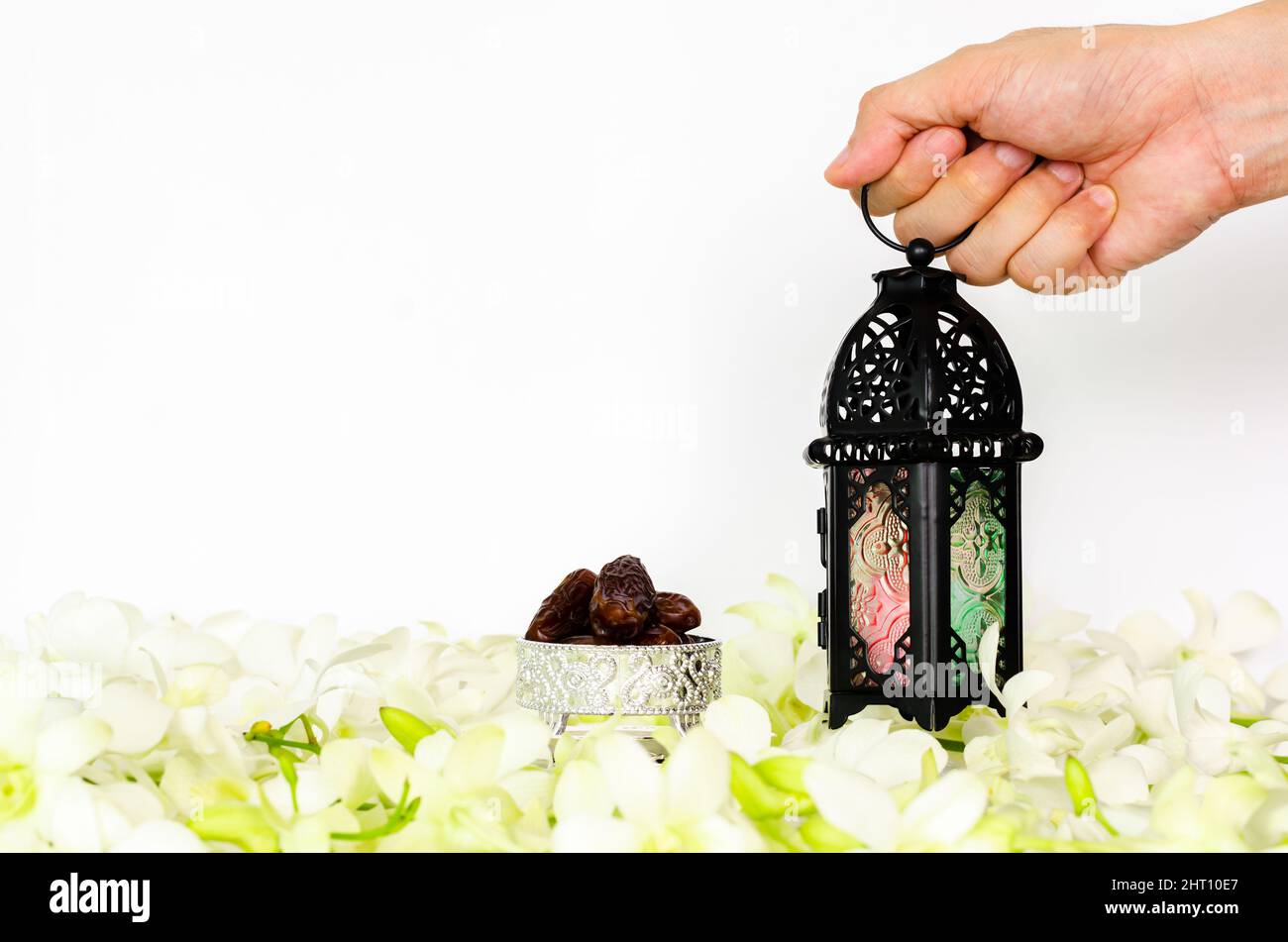 Lanterna a mano su sfondo bianco con datteri frutta su fiore di orchidea per la festa musulmana del mese santo di Ramadan Kareem. Foto Stock