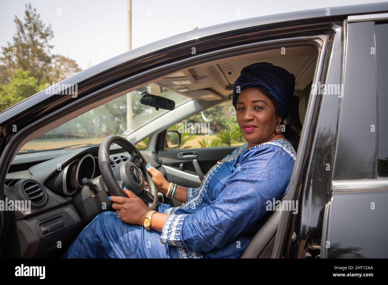 Donna africana seduta all'interno dell'auto con le mani che afferra il volante Foto Stock
