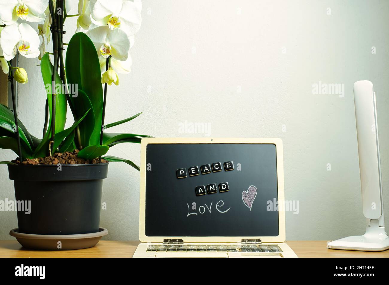 messaggio di pace e di amore. Nella composizione vi è un'orchidea bianca, una postazione di lavoro con scrivania e una lampada. Foto Stock