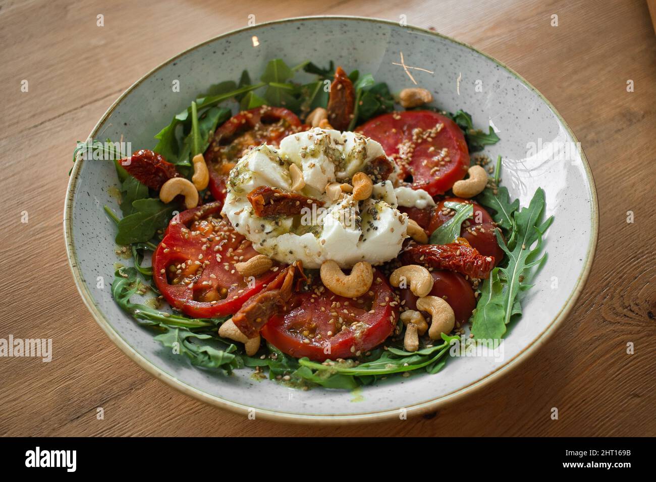 Primo piano di sana insalata italiana con pomodori secchi e freschi, mozzarella, rucola, anacardi, sesamo e pesto di basilico. Fotografia alimentare per sito web. Foto Stock