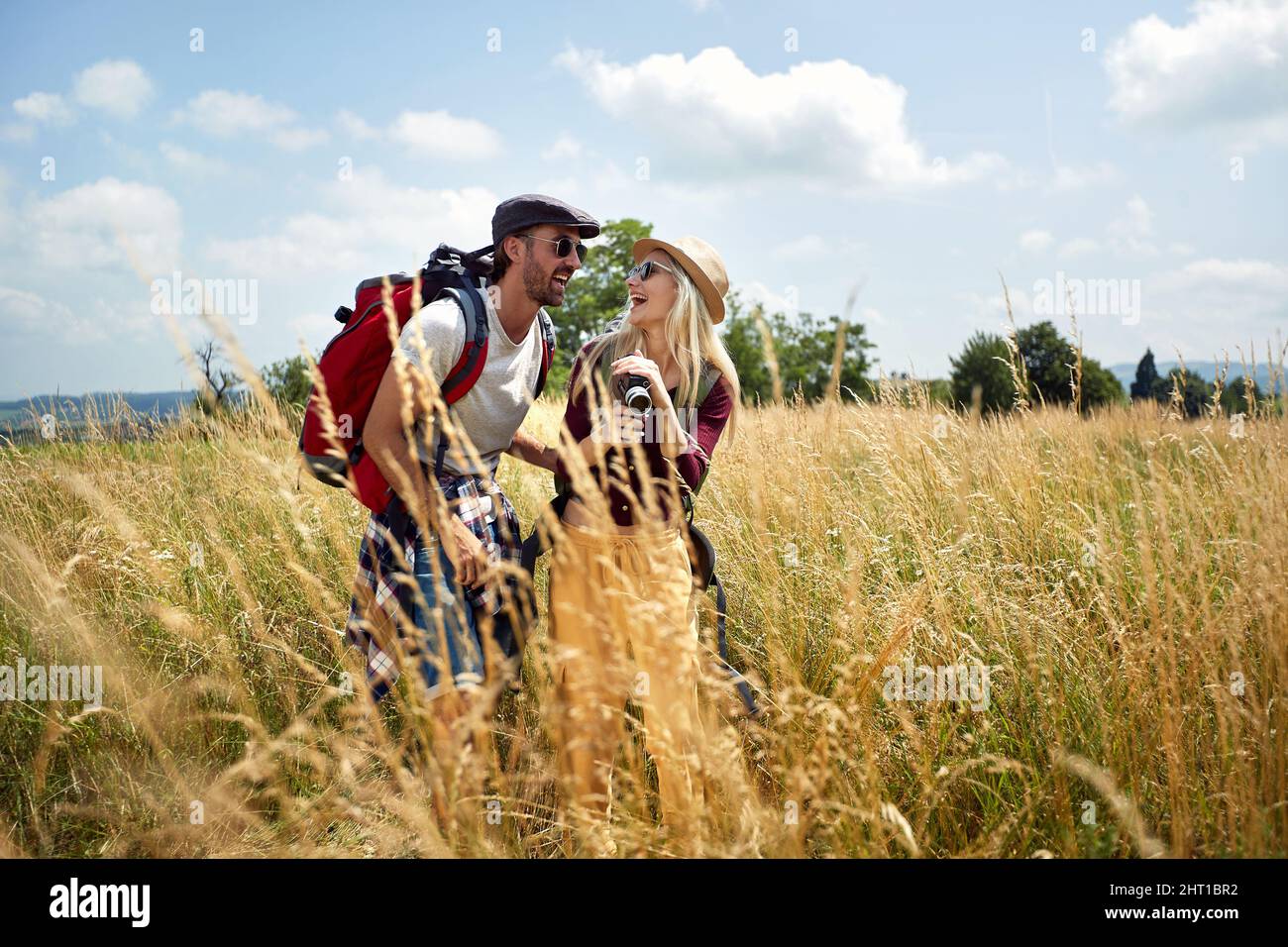 Giovane coppia escursioni con zaino in campo. Divertimento, libertà, concetto di vacanza. Foto Stock