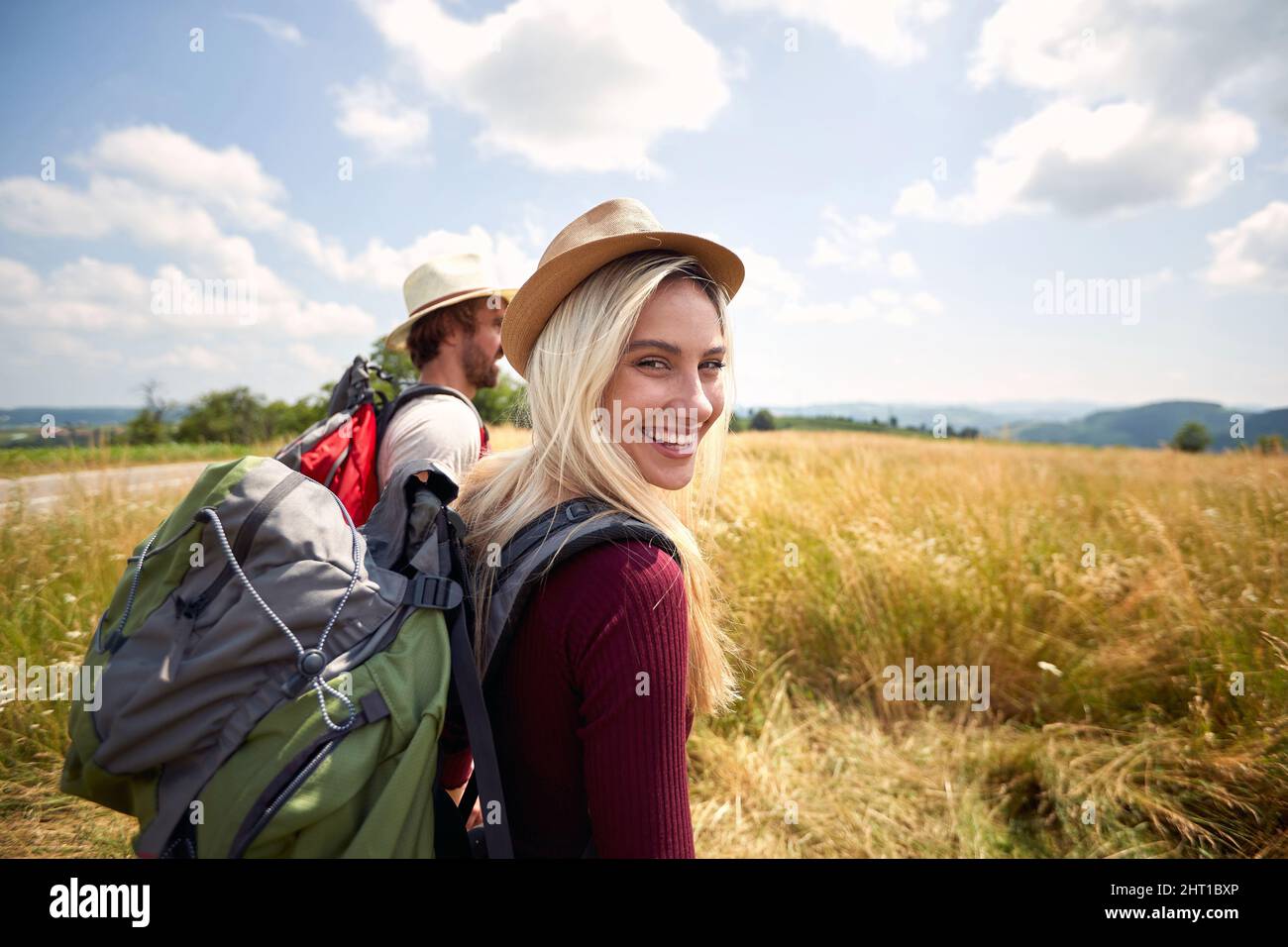 Donna escursionista che sbatte e cammina in campo con un uomo, natura all'aperto. Sport, libertà, concetto di vacanza. Coppia innamorata. Scatto del punto di vista. Foto Stock