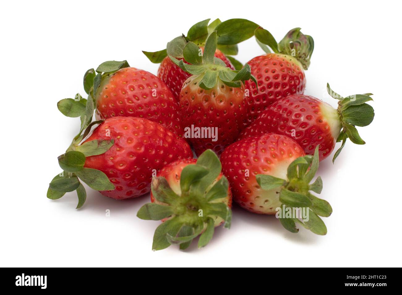 Una manciata di fragole intere con le loro foglie verdi disposte a forma di stella. Isolato su sfondo bianco. Foto Stock