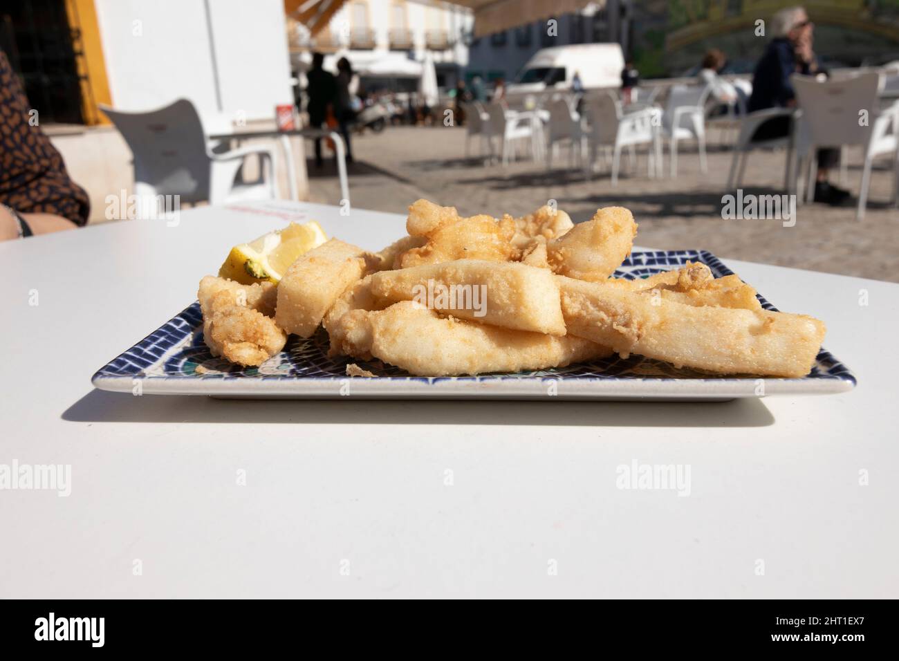 Strisce di seppie fritte, chiamate Chocos Fritos in spagnolo. Servito su un piatto rettangolare decorativo. Cucina spagnola. Foto Stock