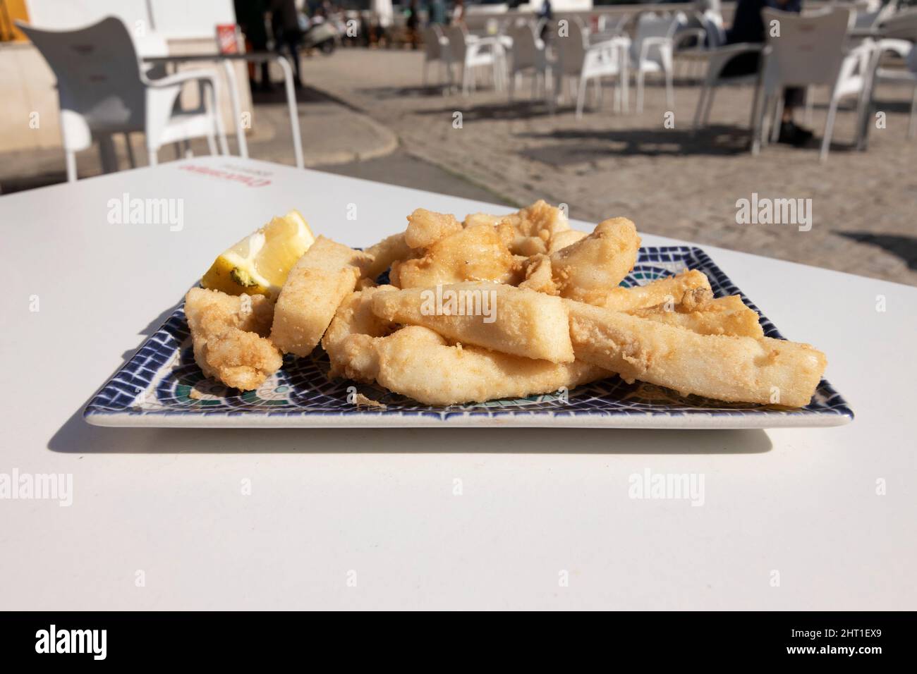 Strisce di seppie fritte, chiamate Chocos Fritos in spagnolo. Servito su un piatto rettangolare decorativo. Cucina spagnola. Foto Stock
