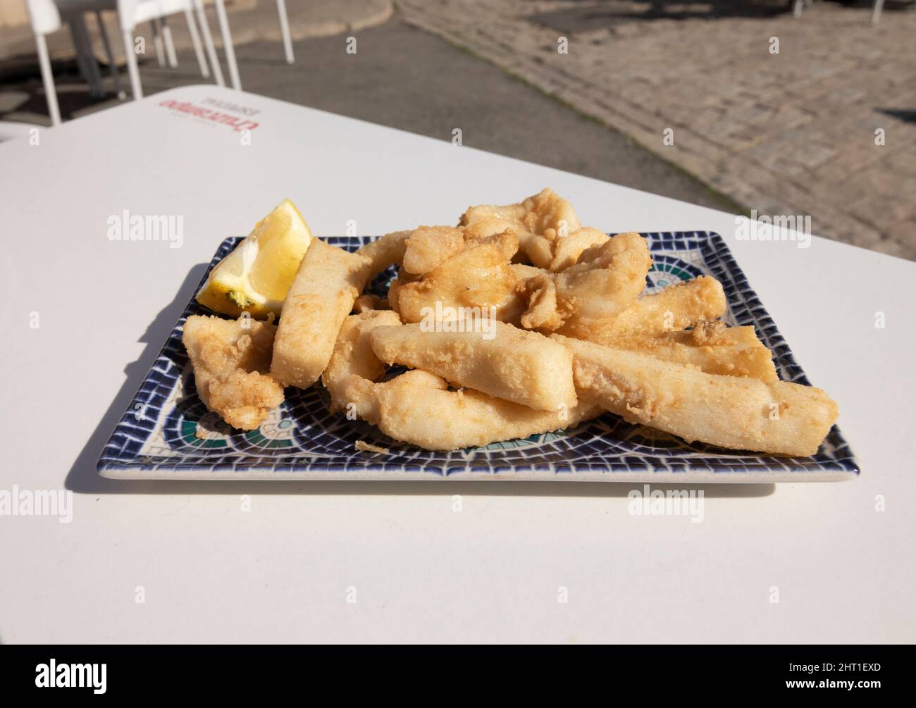 Strisce di seppie fritte, chiamate Chocos Fritos in spagnolo. Servito su un piatto rettangolare decorativo. Cucina spagnola. Foto Stock