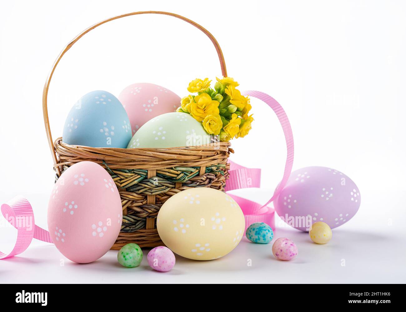 Uova e fiori di pasqua colorati in un cestino e su sfondo bianco Foto Stock