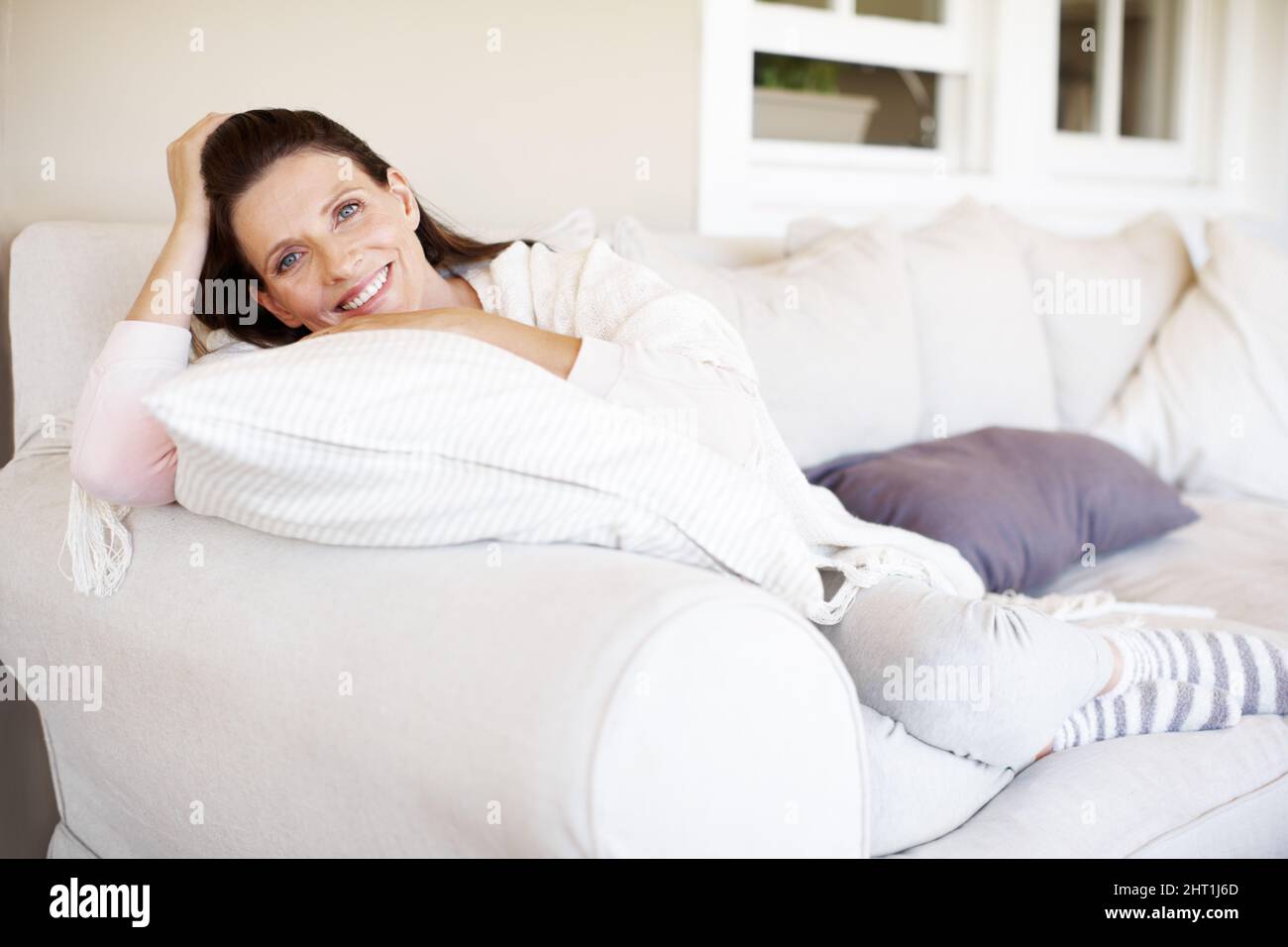 Shes appena avendo una giornata pigra. Una bella donna brunette rilassante su un divano interno. Foto Stock