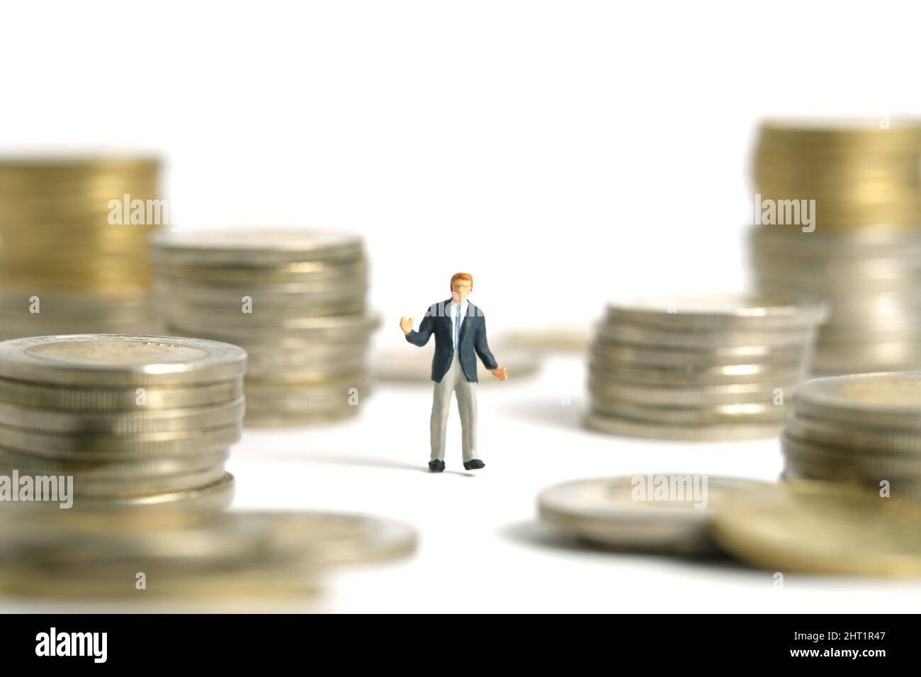 Fotografia di personaggi giocattolo in miniatura. Concetto di piano finanziario. Un uomo d'affari che si batte sopra la pila di soldi della moneta e la pila. Isolato sul retro bianco Foto Stock