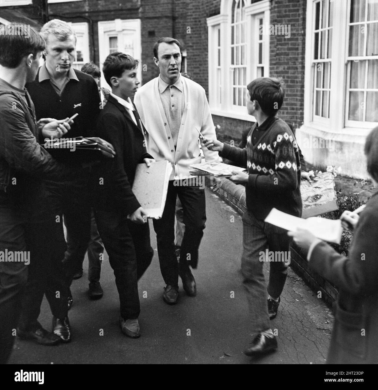 I calciatori inglesi Bobby Moore e Jimmy Greaves sono supplicati dai giovani cacciatori di autografi mentre la squadra inglese lascia il loro Hendon Hall Hotel per il cinema per guardare "Those Magnificent Men in Third Flying Machines" alla vigilia della finale della Coppa del mondo 1966. 29th luglio 1966. Foto Stock