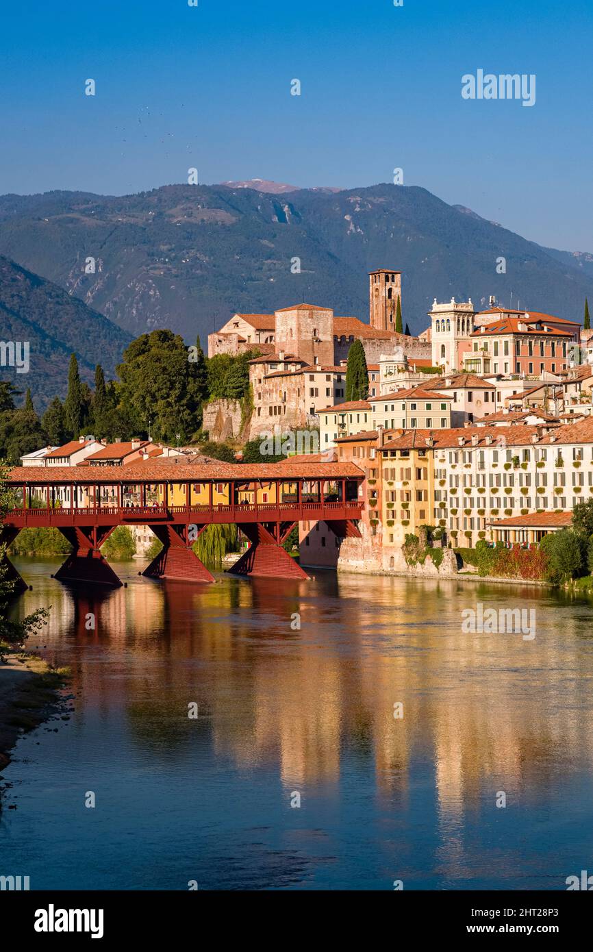 Il ponte Vecchio, Ponte degli Alpini, che conduce sul fiume Brenta a Bassano del Grappa, facciate di case medievali che si riflettono nell'acqua. Foto Stock
