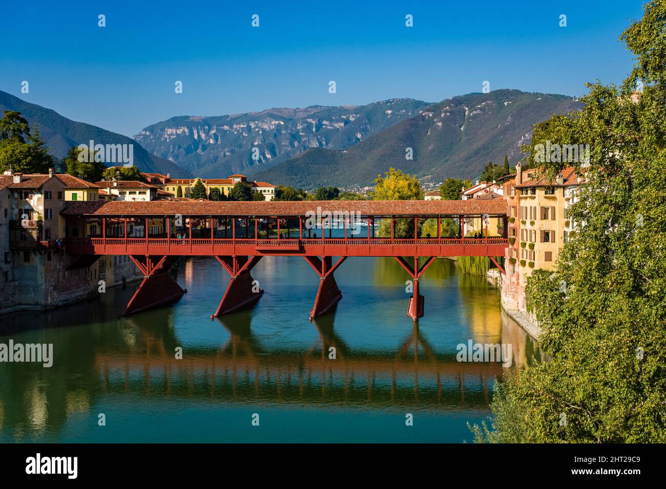 Il ponte Vecchio, Ponte degli Alpini, che conduce sul fiume Brenta a Bassano del Grappa, in lontananza ai piedi del Monte Grappa. Foto Stock
