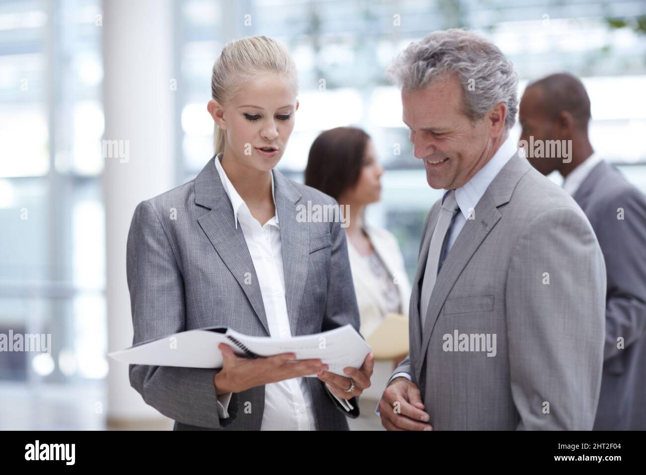 Cercando il suo consiglio rispettato. Una donna d'affari graziosa che presenta un raccoglitore ad un esecutivo superiore impressionato. Foto Stock