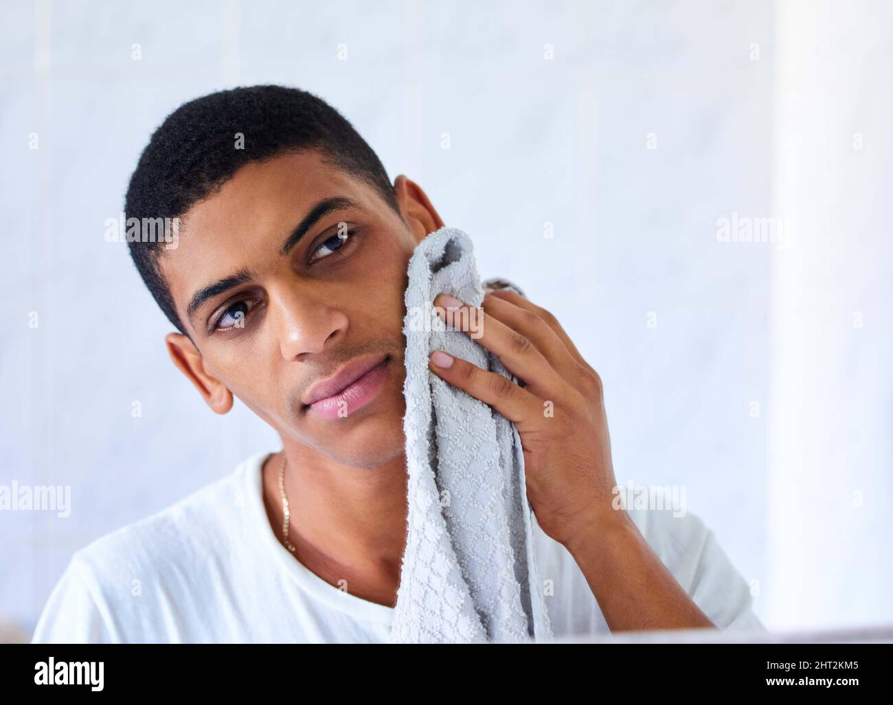 Una routine di cura della pelle del mattino è altrettanto importante per una notte. Scatto corto di un bel giovane uomo con un asciugamano per strofinare il viso la mattina alle Foto Stock