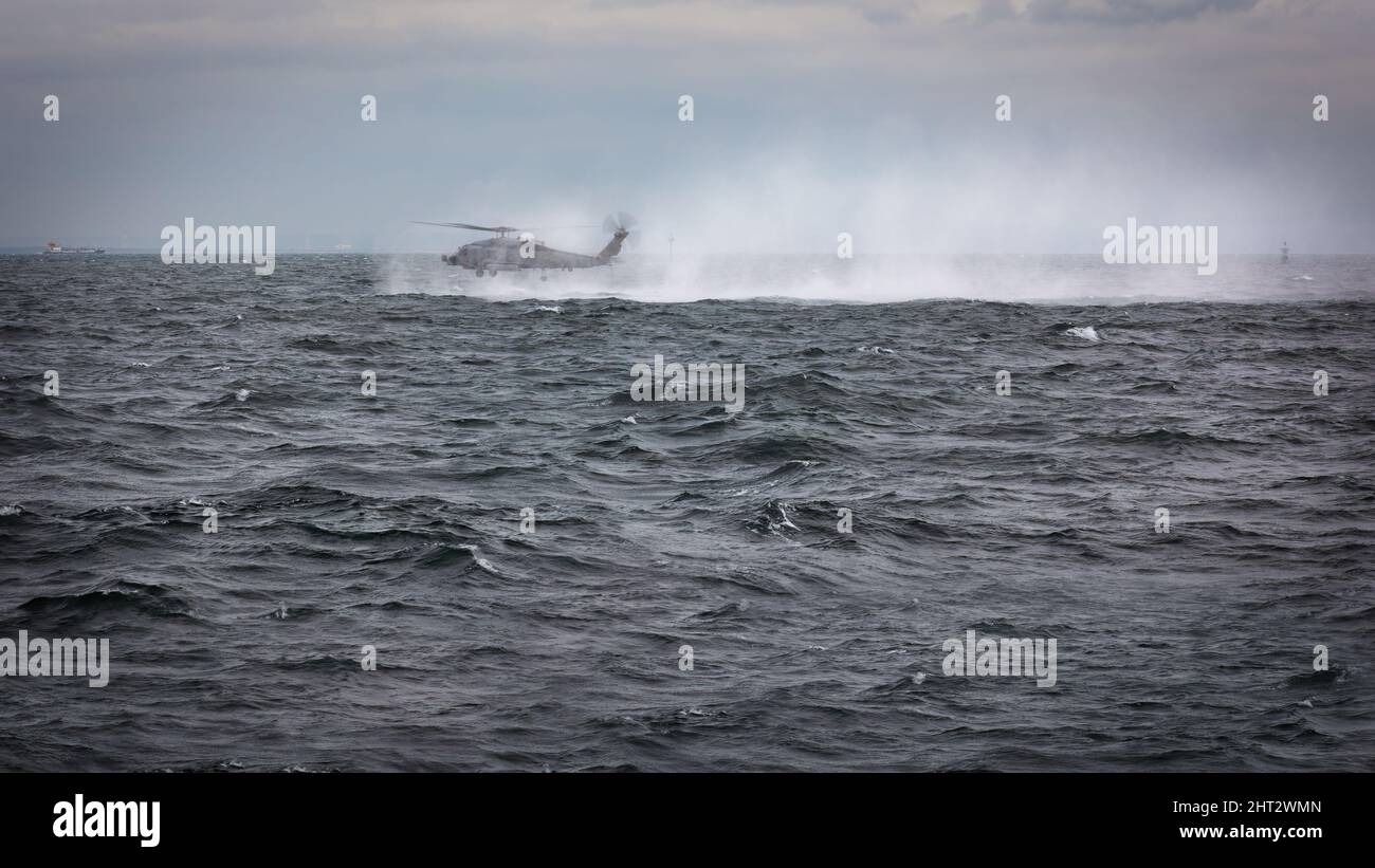 Un elicottero della Marina degli Stati Uniti MH-60, volando lento e lento, prima di far cadere un nuotatore di salvataggio in acqua mentre si allenano al largo della costa vicino a Yokosuka, Giappone. Foto Stock