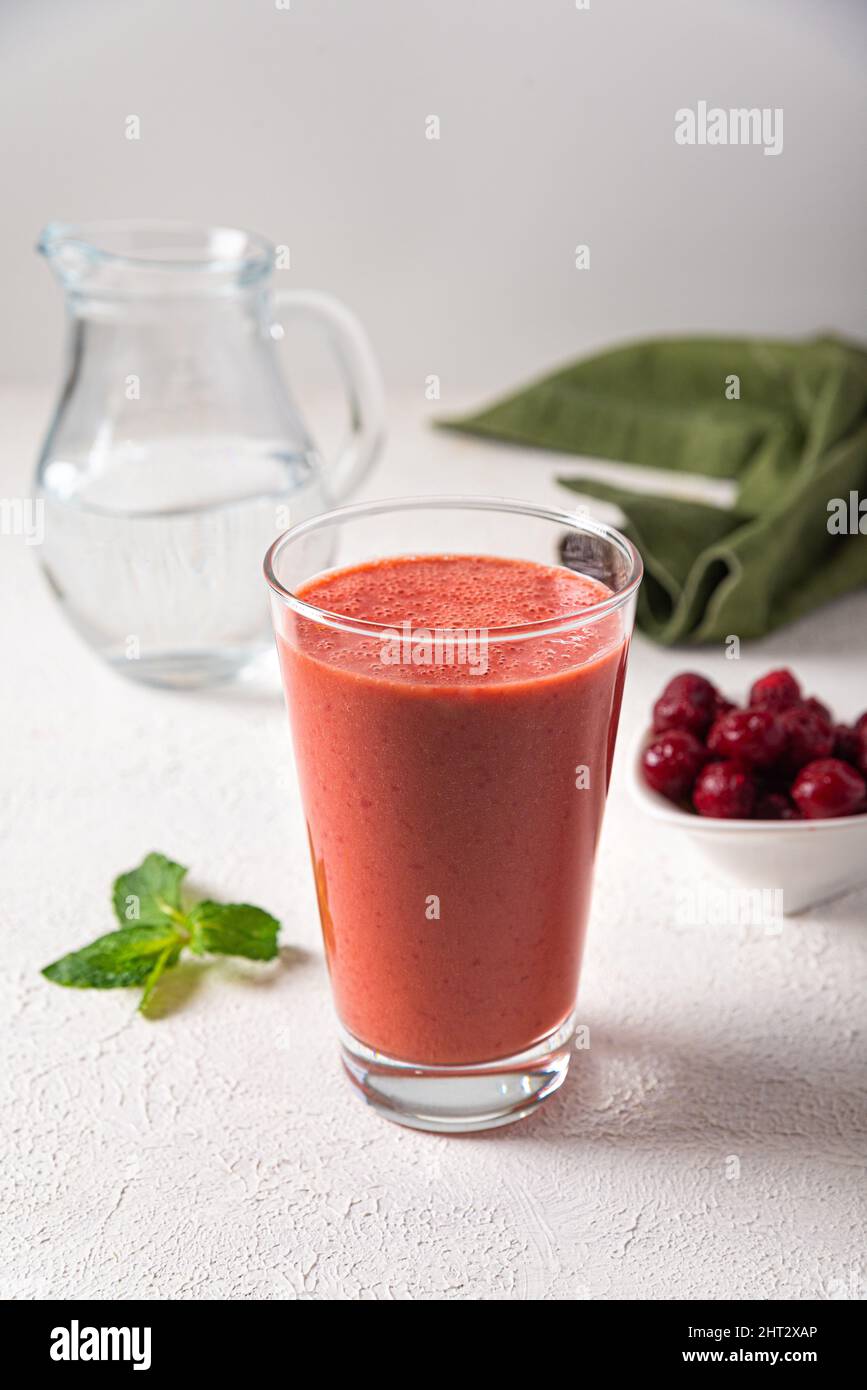 frullato alla ciliegia in vetro. frutti di bosco di ciliegia mescolati con acqua. frullato estivo fresco. bevanda rinfrescante. Foto Stock
