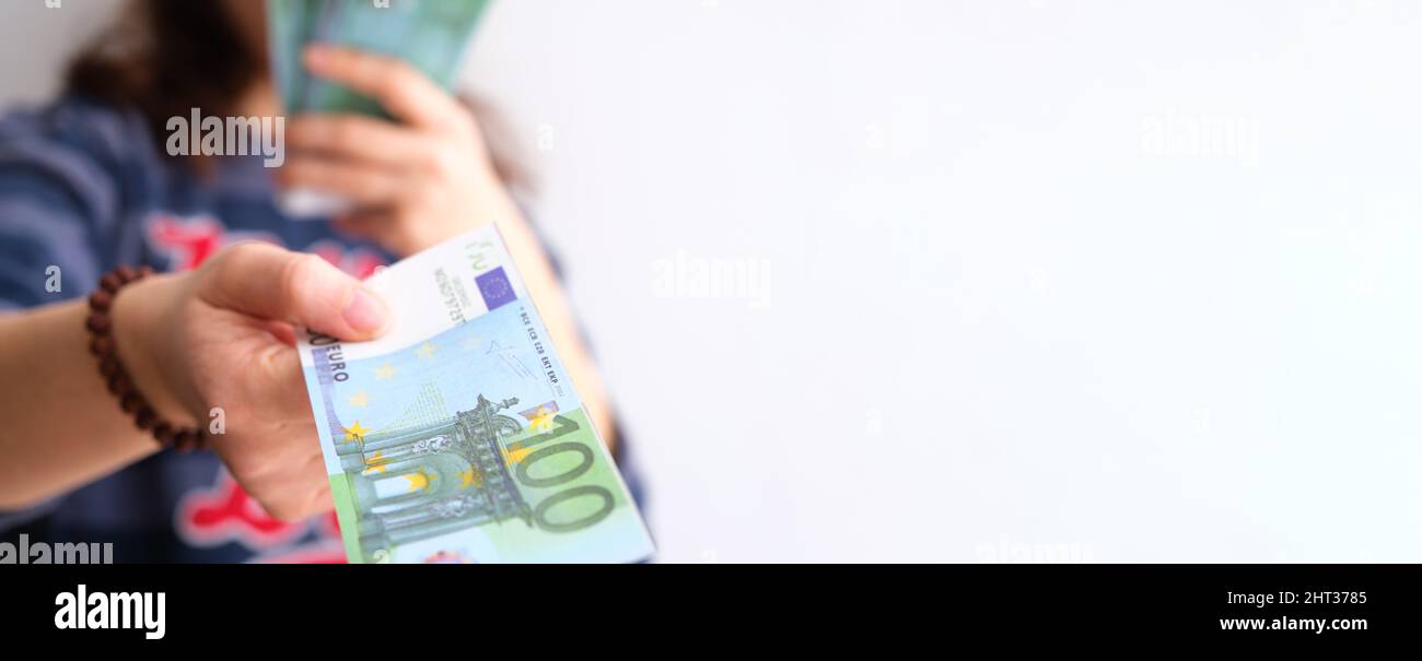 Mano femminile che dà una banconota di denaro per un pagamento su sfondo bianco, primo piano di ragazza caucasica adulta che consegna la moneta dell'Unione europea. Foto Stock