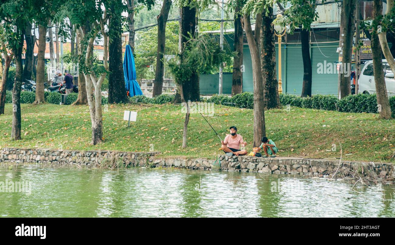Padre e figlio pesca sul lago con case sullo sfondo Foto Stock