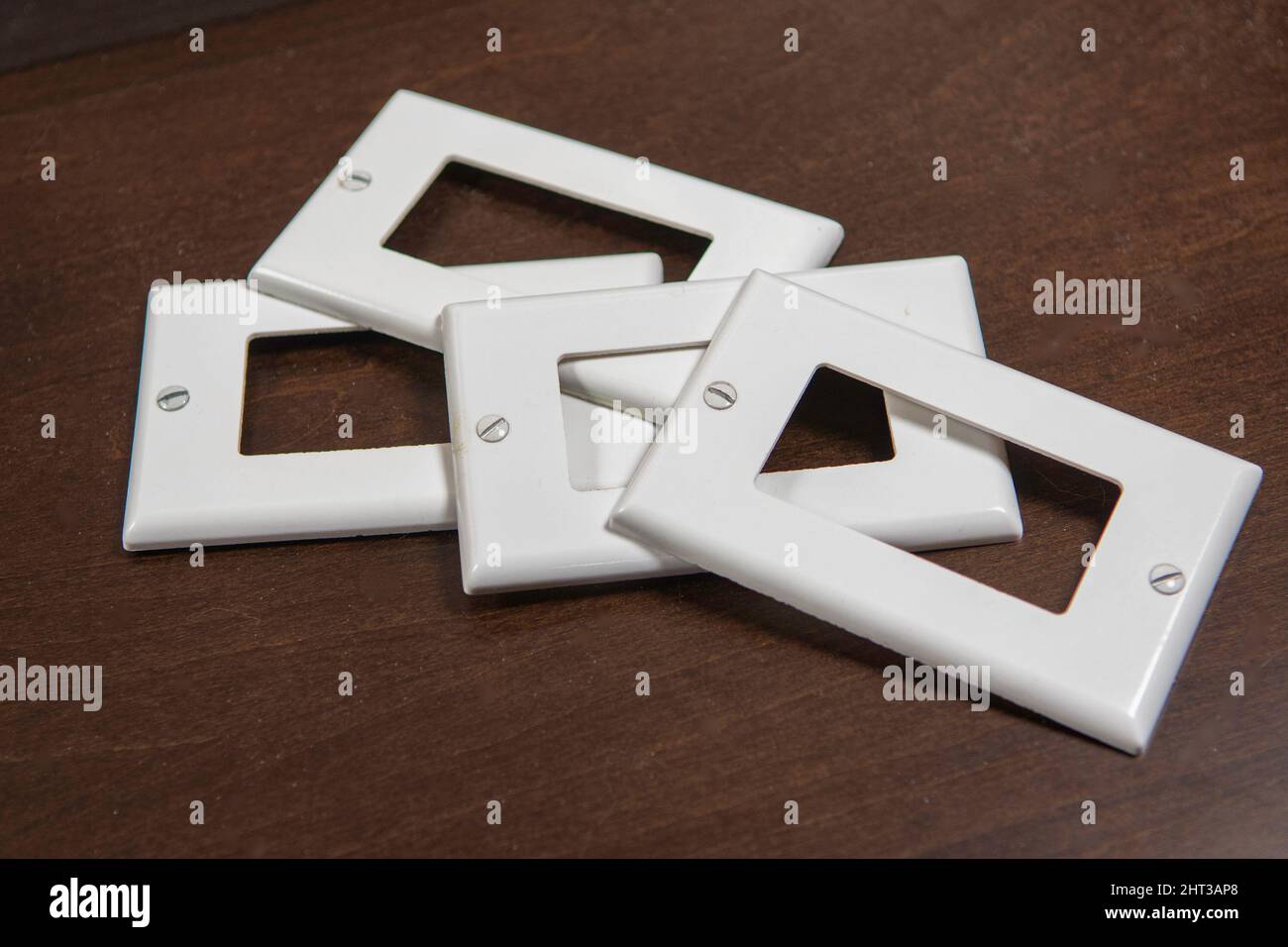 Due interruttori, una presa e tre coperchi in plastica decorativi bianchi separati per una presa o un interruttore Foto Stock