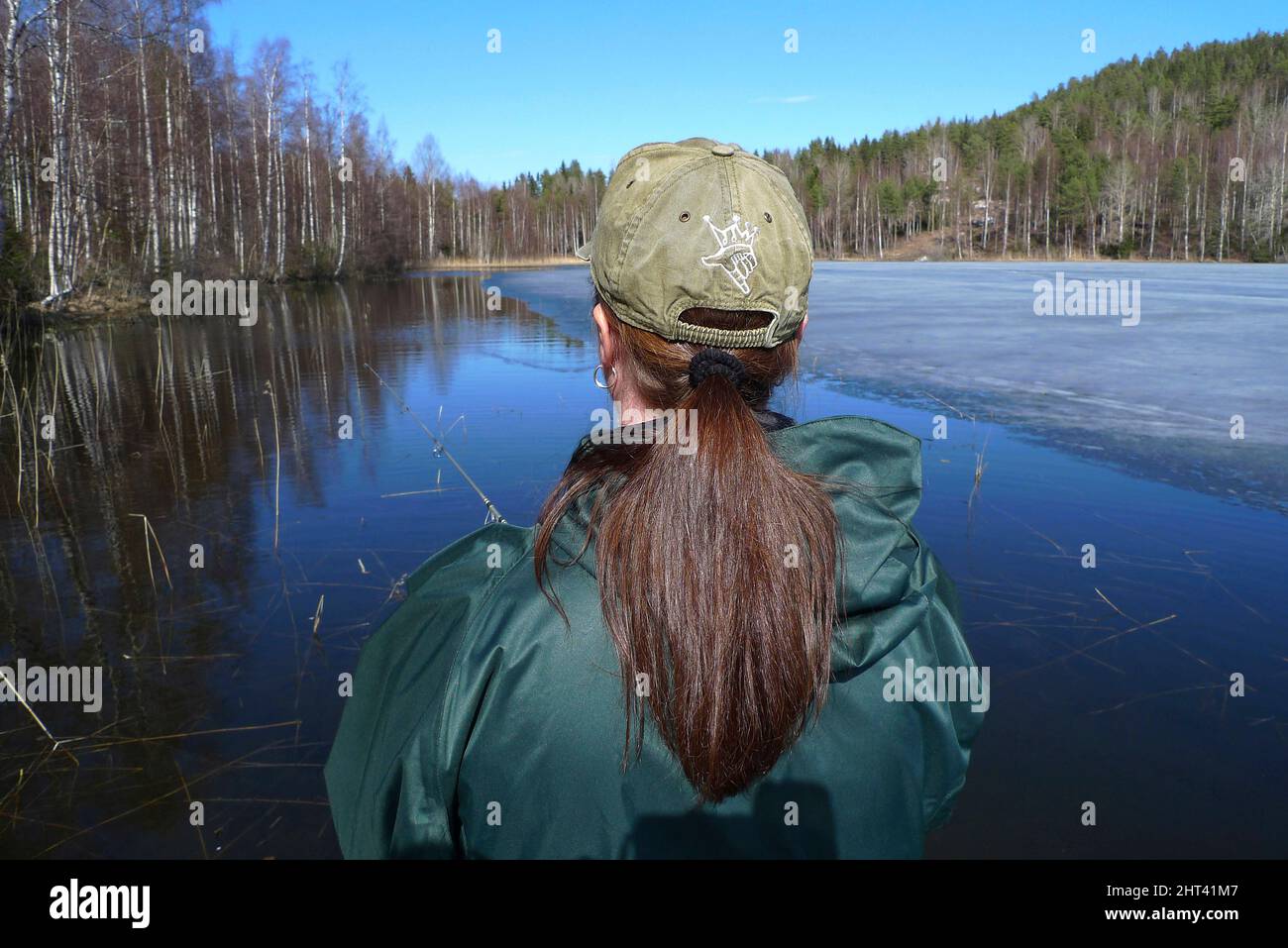 Donna che pesca in lago con ghiaccio di primavera Foto Stock