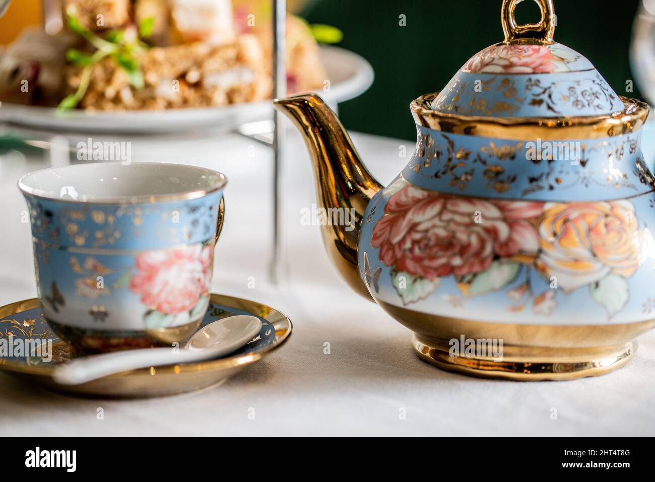 Primo piano della teiera floreale in porcellana e della tazza su un tavolo bianco Foto Stock