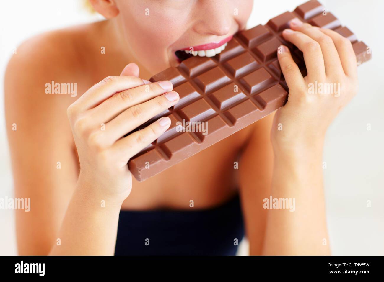 Niente altro che indulgenza peccaminosa. Vista ritagliata di una giovane donna  che mordicchiava in una grande lastra di cioccolato Foto stock - Alamy