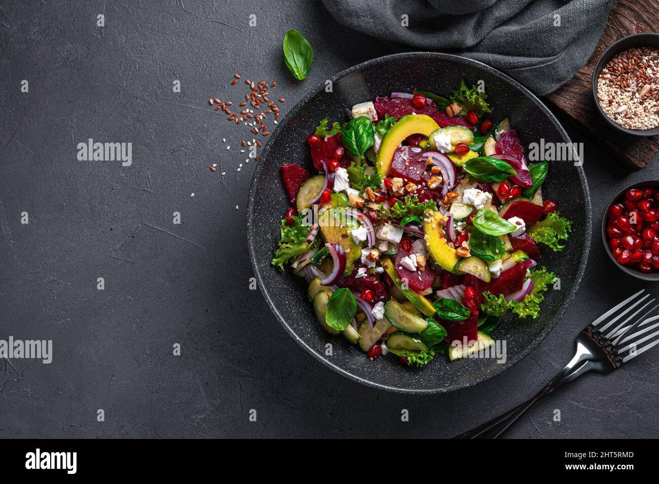 Insalata con barbabietole, avocado, cetrioli e feta conditi con melograno, noci, semi di lino e sesamo. Foto Stock