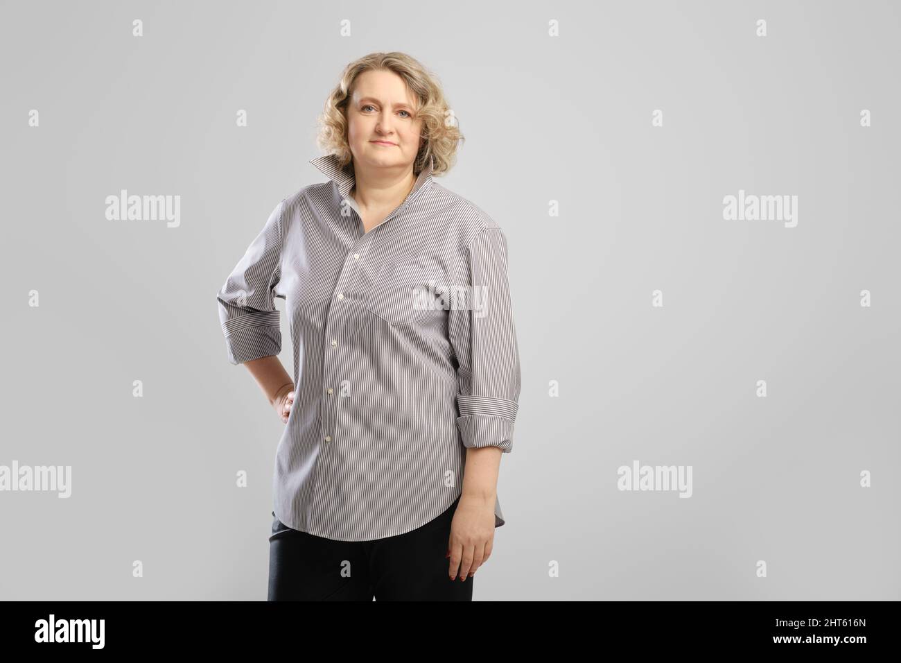 Ritratto casual di donna anziana in camicia grigia e pantaloni su sfondo  grigio studio Foto stock - Alamy