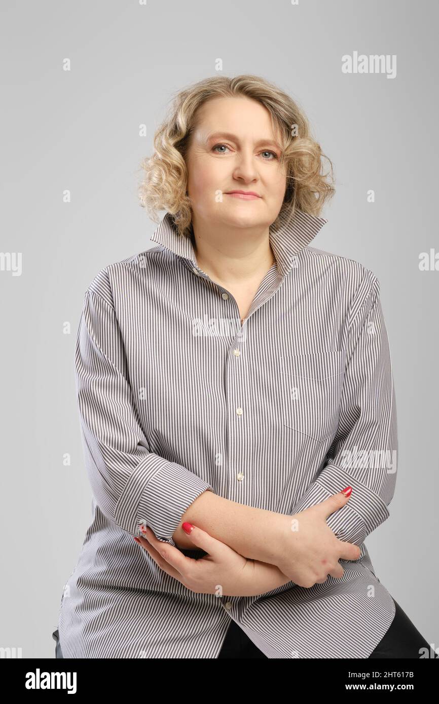 Ritratto da studio di donna anziana in camicia grigia a braccia incrociate Foto Stock