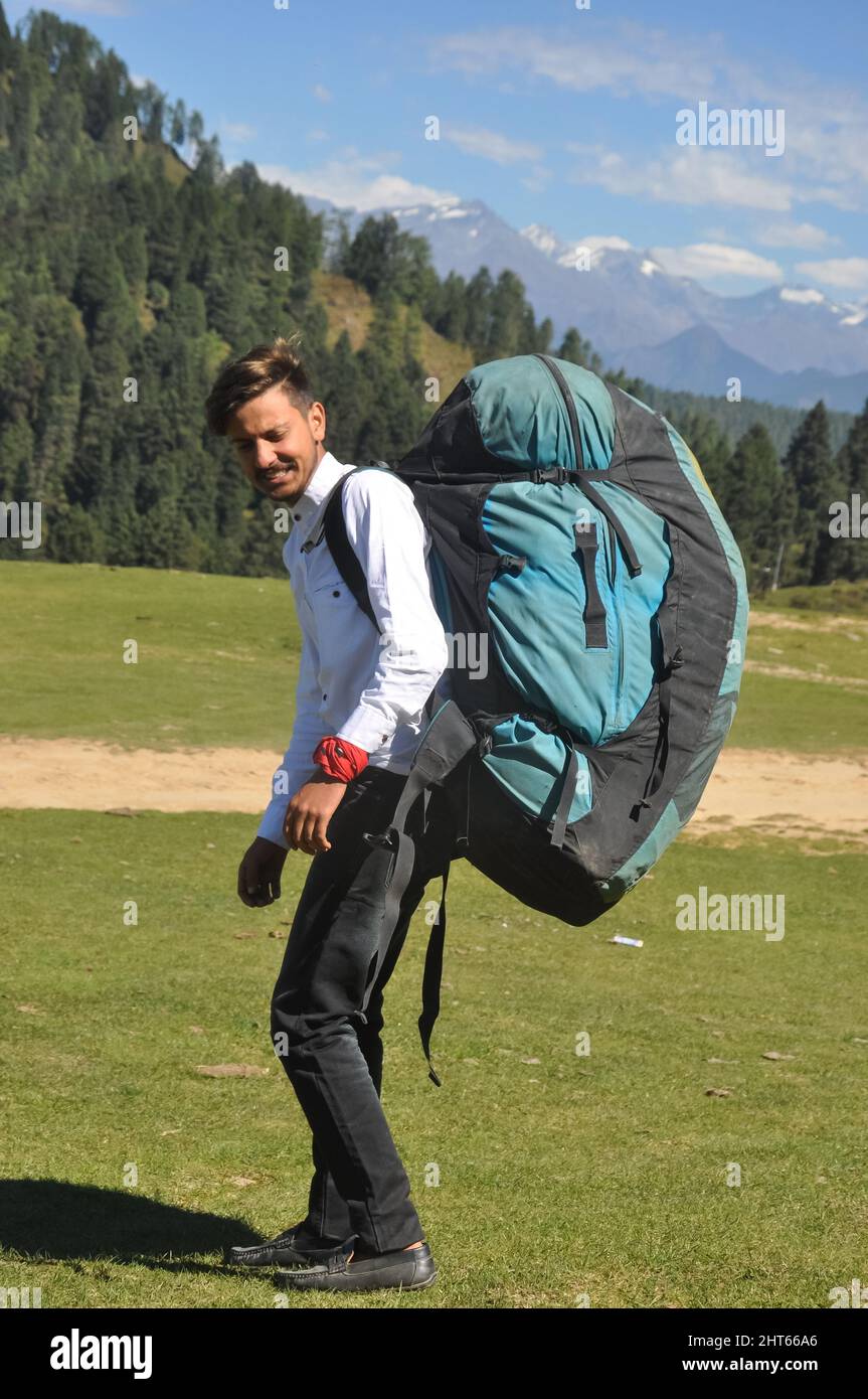 Vista posteriore di un giovane turista maschio a piedi con trasporto sacchetto paracadute in montagna Foto Stock