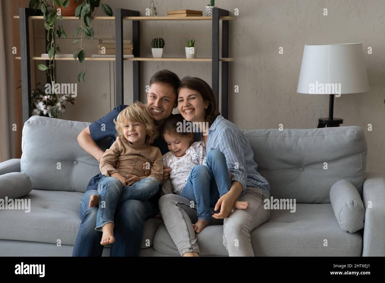 Felici genitori affettuosi che riposano con bambini carini a casa. Foto Stock