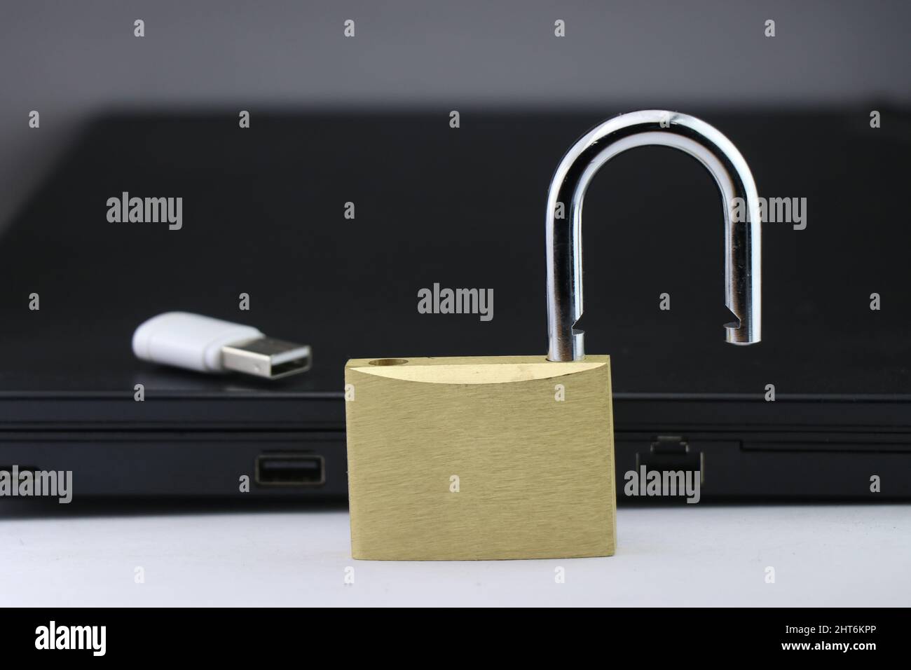 Concetto di sicurezza informatica o sicurezza dei dati utilizzando un lucchetto metallico con un dispositivo di archiviazione dati e un notebook in background Foto Stock