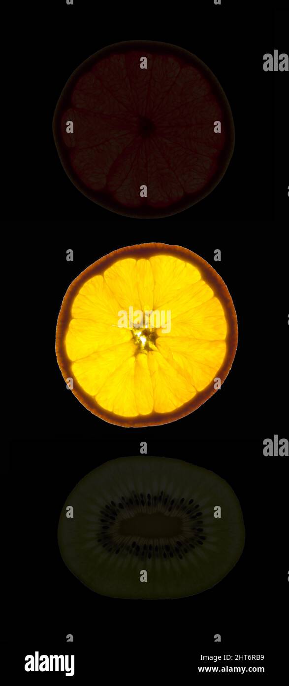 Luce gialla sul semaforo composta da fette retroilluminate di agrumi maturi Foto Stock