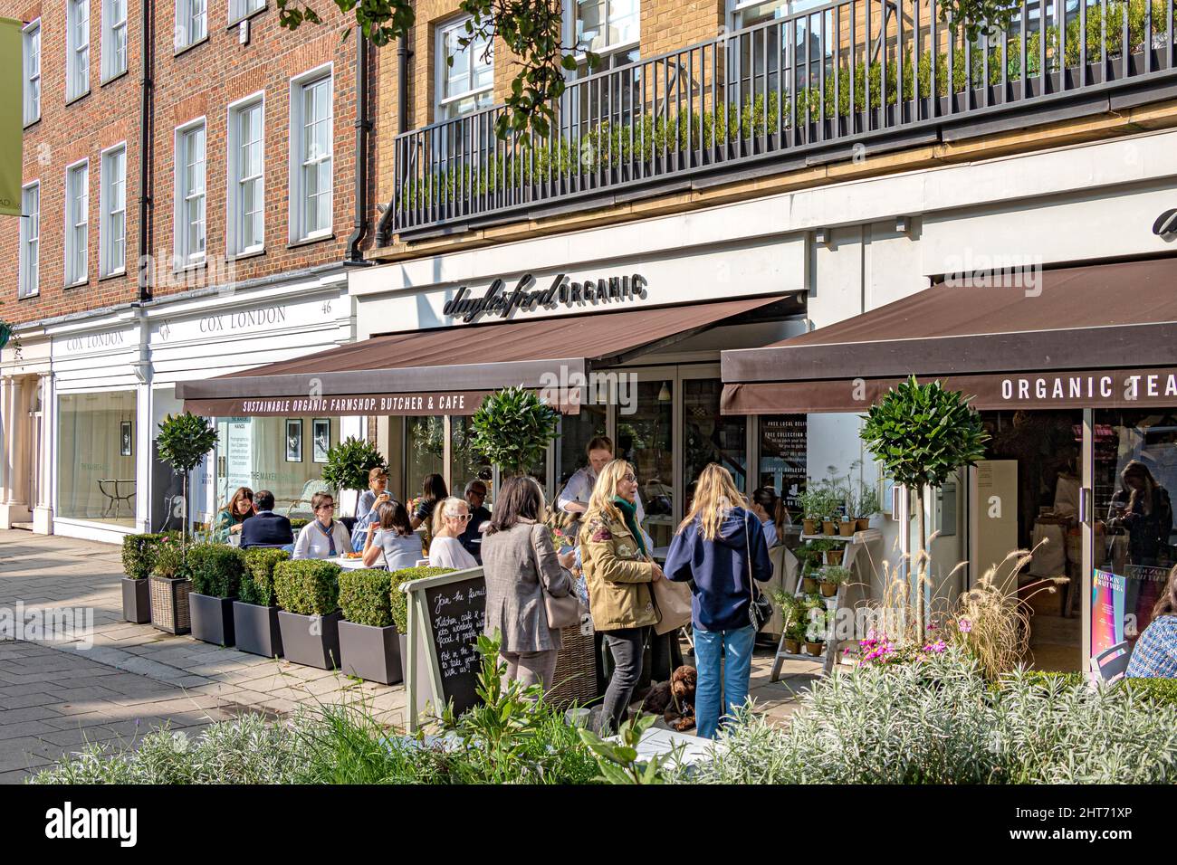 Persone sedute fuori sulla terrazza fuori dal negozio Dalyesford Organic Farm in Pimlico Road, Belgravia in una mattinata di sole, Londra, SW1 Foto Stock