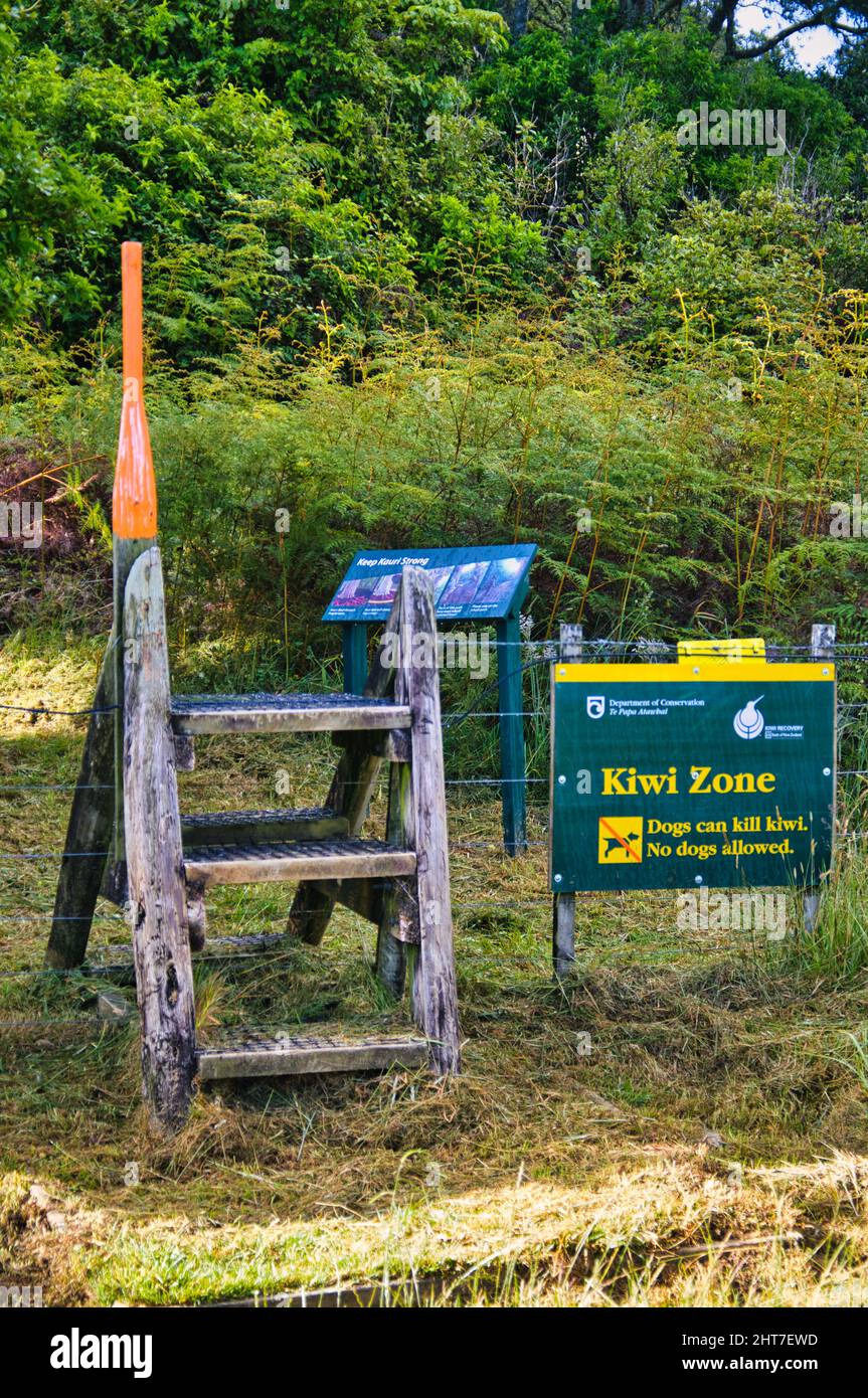 Stiglia di legno e un cartello Kiwi zone, che indica un'area di protezione per i kiwi. In un sentiero attraverso la Foresta di Pukenui, Whangarei, Isola del Nord, Nuova Zelanda Foto Stock
