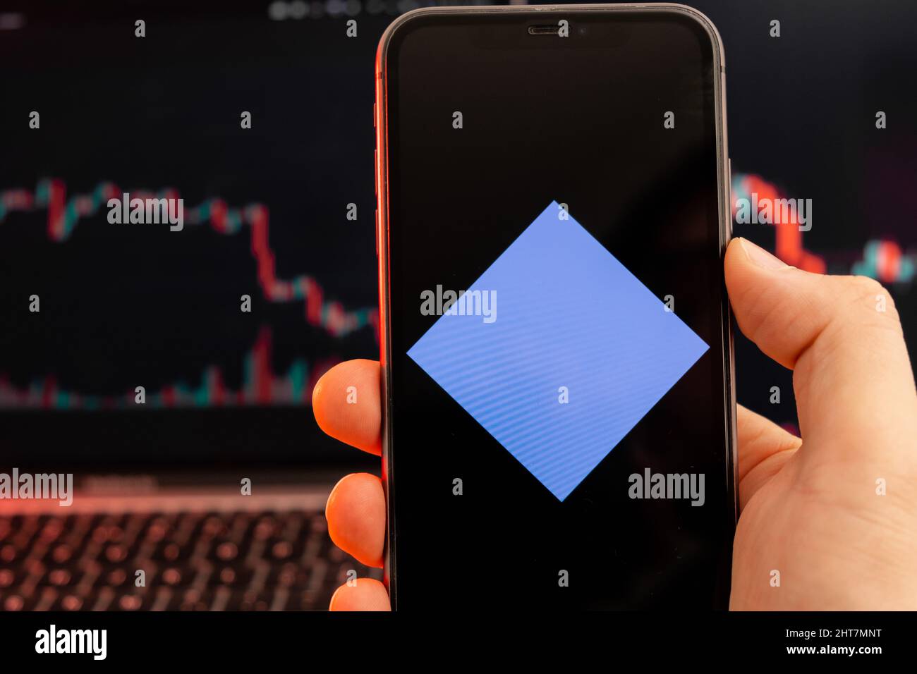 Waves WAVES Cryptocurrency logo sullo schermo di smartphone in mano mans con tendenza al ribasso sulla carta su sfondo rosso, febbraio 2022, San Francisco, USA. Foto Stock
