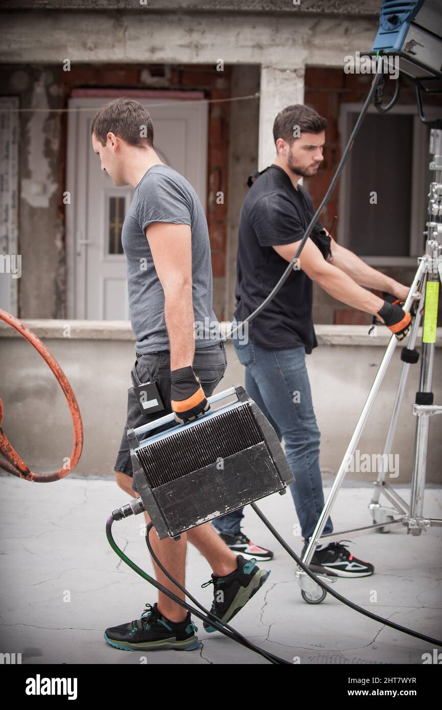 Dietro la scena. Tecnico di illuminazione filmmaking ingegnere elettrico regolazione e impostazione luci per la scena di film. Reparto luce. Film Crew. (Equipaggio pellicola Foto Stock