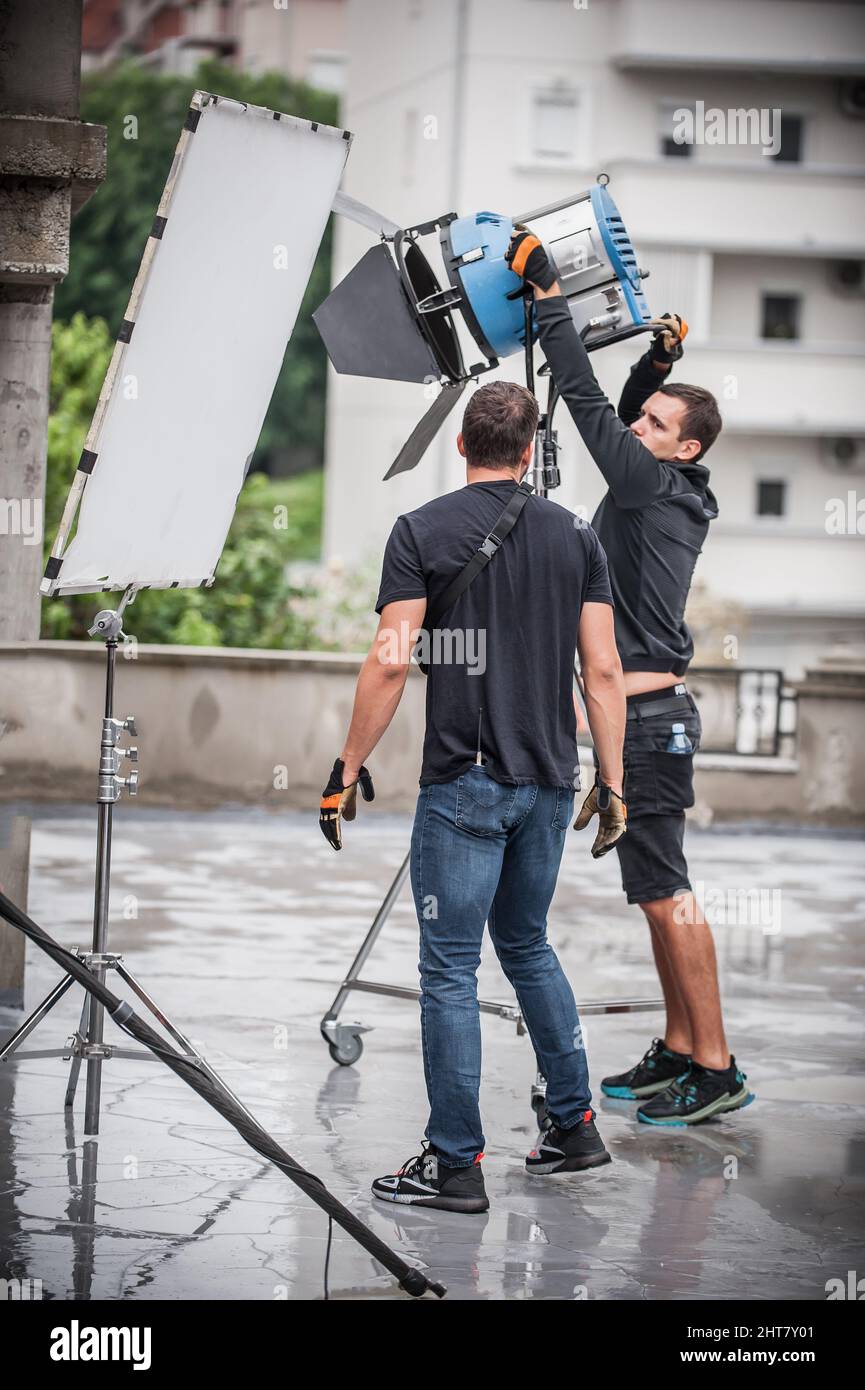 Dietro la scena. Tecnico di illuminazione filmmaking ingegnere elettrico regolazione e impostazione luci per la scena di film. Reparto luce. Film Crew. (Equipaggio pellicola Foto Stock