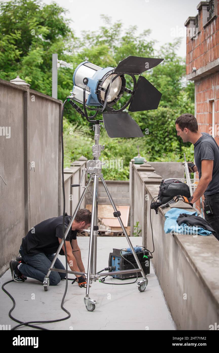 Dietro la scena. Tecnico di illuminazione filmmaking ingegnere elettrico regolazione e impostazione luci per la scena di film. Reparto luce. Film Crew. (Equipaggio pellicola Foto Stock