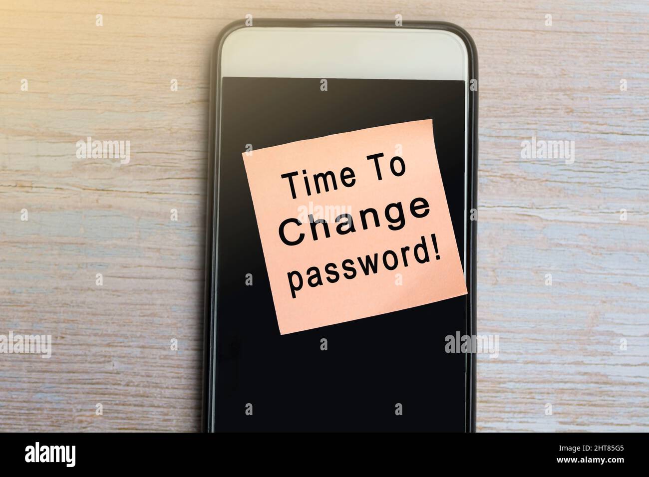 È ora di cambiare il testo della password su blocco note con smartphone su scrivania in legno. Foto Stock